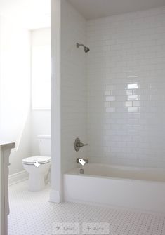 a white bathroom with a toilet and bathtub