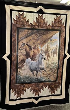 a quilt with horses on it is hanging from the ceiling in a room that has carpeted flooring