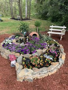 a garden with flowers and plants in it next to a bench on the side of a road