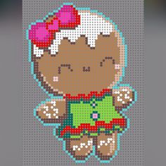 a cross stitch teddy bear with a green shirt and red bow on it's head