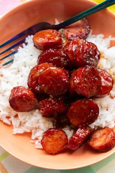 a bowl filled with rice and sausage next to chopsticks on top of it