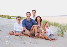 a family sitting in the sand at the beach