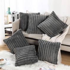 four pillows on a white rug in front of a couch