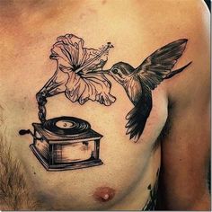 a man with a tattoo on his chest has a hummingbird flying over a record and flower