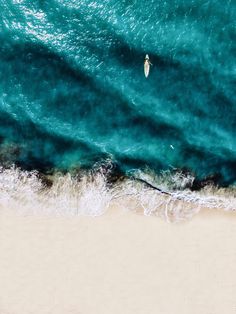 an aerial view of the ocean with a surfboard in the water