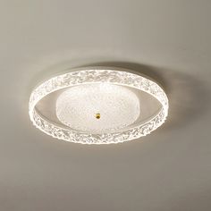 a white ceiling light with an intricate design on the top and bottom part is lit up