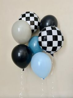 black, white and blue balloons with checkerboard design on them are hanging from the wall