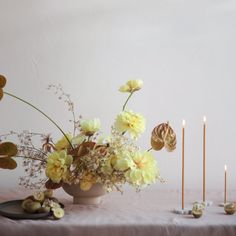 a table topped with yellow flowers and candles