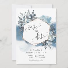 save the date card with blue watercolor paint and gold foil on it, surrounded by greenery