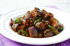 a white plate topped with cooked eggplant and sesame seeds on top of it