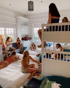 a group of women sitting on top of bunk beds in a room with white walls