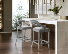 two white bar stools sitting in front of a counter