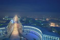 an aerial view of a city at night with snow on the ground and buildings lit up