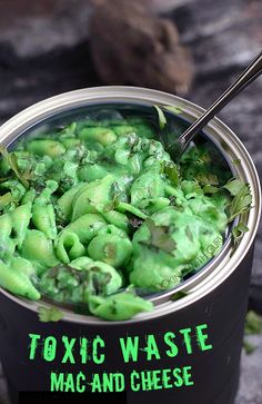 a pot filled with green food on top of a wooden table next to a spoon