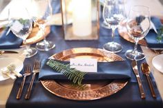 the table is set with gold and black plates, silverware, and place settings