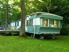 a mobile home sits in the middle of a wooded area next to a picnic table