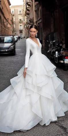 a woman in a wedding dress standing on the street