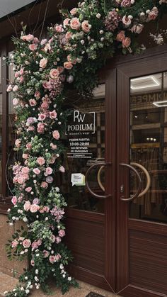 the entrance to a flower shop with pink and white flowers growing up it's side