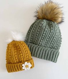 two knit hats with pom - poms on them, one is green and the other is yellow