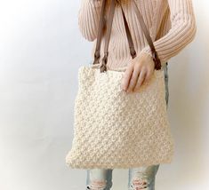 a woman holding a crocheted bag with the text, the aspen knit bag free pattern