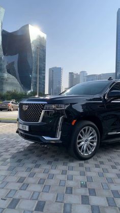 a black suv parked in front of a large cityscape with tall buildings behind it