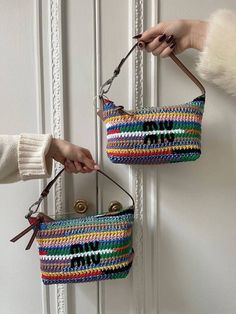 two handmade purses are hanging on the door handle, one is multicolored