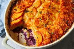 a casserole dish with potatoes and carrots in it on a blue cloth