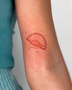 a woman's arm with a red tattoo design on the left side of her arm