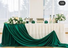 the table is covered with green cloth and white flowers