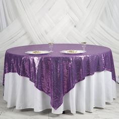 the table is covered with purple sequins and two silver plates are on it