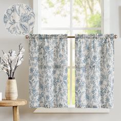 a window with blue and white curtains next to a vase filled with flowers on top of a table