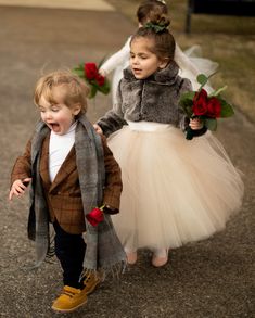 two young children dressed up in costumes walking down the street with roses on their hands