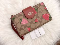 Coach Phone Wallet In Signature Canvas With Wild Strawberry Print Brand New With Tags 100% Authentic Color: Gold/Khaki Multi Signature coated canvas and smooth leather Six credit card slots ID window Snap phone compartment Snap closure Outside zip pocket Attached wrist strap 7 1/4" (L) x 4 1/2" (H) Fits all iPhone and Samsung Galaxy phones Style No. CH165 Coach Strawberry Collection, Coach Strawberry Wallet, Coach Strawberry, Window Snap, Pretty Purses, Samsung Galaxy Phones, Wild Strawberry, Wild Strawberries, Strawberry Print