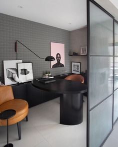 an office with a black table and chairs in front of a large glass door that leads to another room