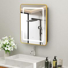 a bathroom sink sitting under a mirror next to a white vase with flowers in it