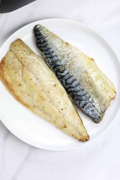 two fish are on a white plate next to each other, one is cooked and the other is uncooked