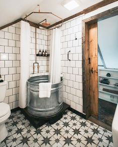 a bathroom with black and white tiled floors and walls, along with a large tub in the center