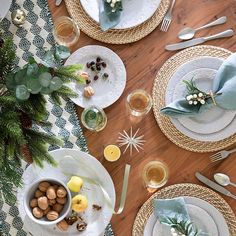 the table is set with plates, silverware and green napkins for christmas dinner