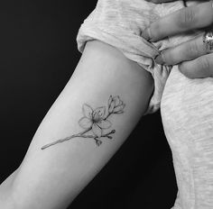 a woman's arm with a small flower tattoo on the left side of her right arm