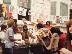 a group of people standing in front of a building with posters hanging on the wall