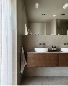 a bathroom with two sinks and mirrors on the wall next to a curtained window