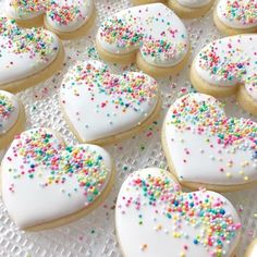 many heart shaped cookies with sprinkles on a plate