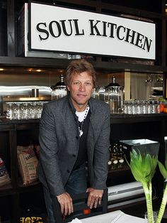 a man standing in front of a table with a vase on it and a sign that says soul kitchen