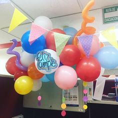 an office cubicle decorated with balloons, streamers and confetti for a birthday party