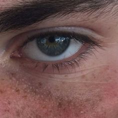 an extreme close up shot of a man's blue eye with freckles