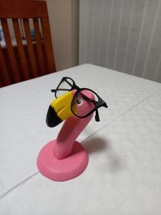 a pink toy with glasses on top of it sitting on a white table cloth covered bed