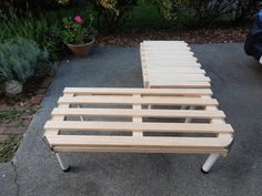 a wooden bench sitting on top of a cement ground next to a planter filled with flowers