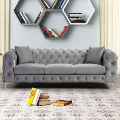 a gray couch sitting on top of a rug next to a book shelf filled with books