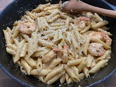 pasta with shrimp and parmesan cheese in a skillet on a wooden table