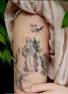 a woman's arm with a tattoo on it and an image of the virgin mary